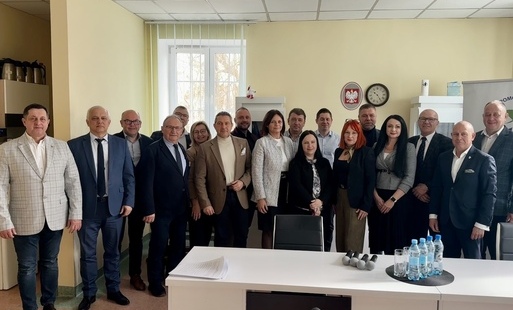 grupa ludzi stoi w duzym przestronnym pokoju, pozuje do wspolnej fotografi 